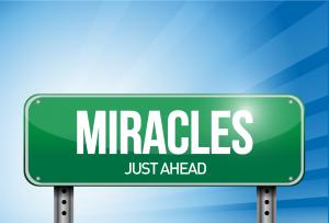Street sign that reads Miracles Just Ahead
