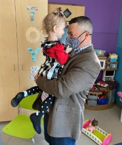 Masked provider holding female toddler