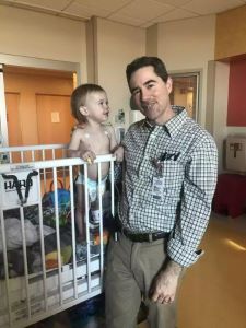 Provider standing next to toddler in crib