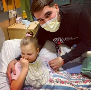 Masked provider next to patient in hospital bed