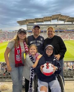 Family of 5 posing near a soccer field