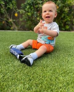 Toddler with leg braces, sitting on grass