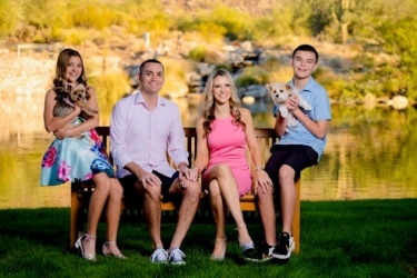 Family of 4 posing on bench with two small dogs