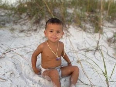Toddler sitting in sand at the beach
