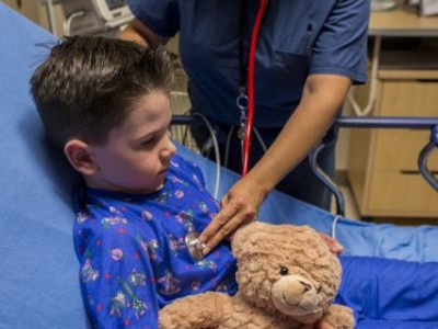Child in hospital bed, getting checked by provider