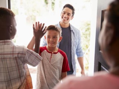 Two boys high-fiving with dad in the background