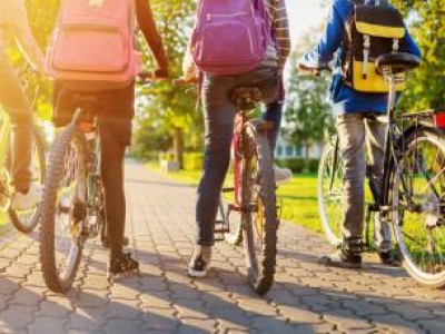 Four kids on bicycles wearing backpacks