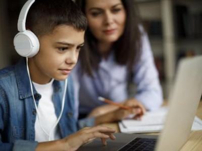 Boy working on laptop while mother looks on
