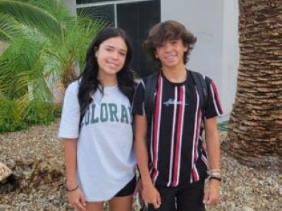 Teenage boy and girl standing outside home, smiling