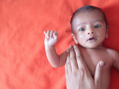 Infant with adult hand on their chest