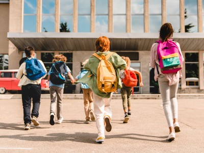 Kids wearing backpacks in front of school