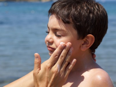 Child getting sunscreen applied to face