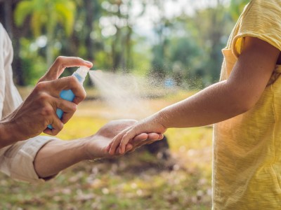 Parent spraying repellant on child's arm