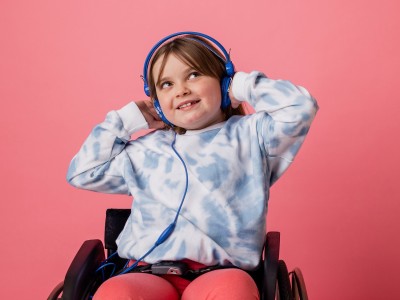 Child in wheelchair, wearing blue headphones