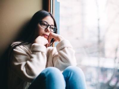 Pensive teen sitting next to window