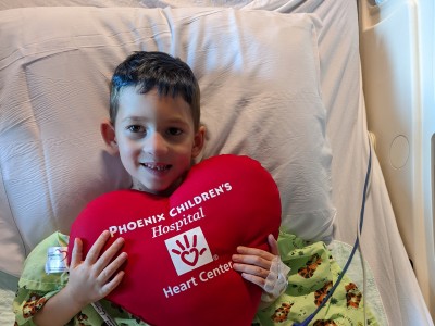 Young boy holding a large heart pillow to his chest