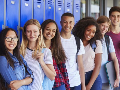 Group of smiling teens standing in front of lockers