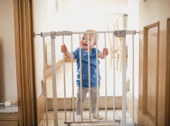 Toddler standing behind a baby gate