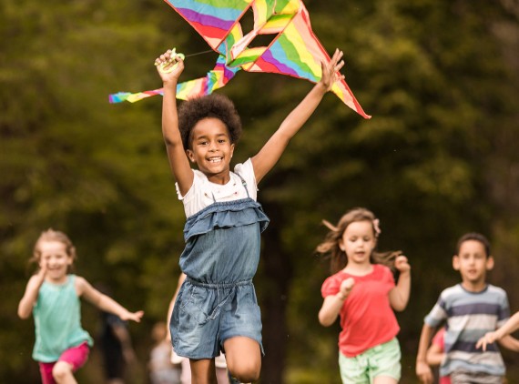 kids running in a field with a kite