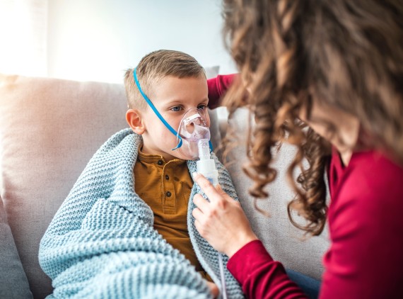 Child in blanket wearing a breathing treatment mask