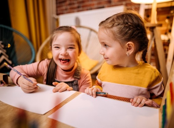 Two young girls drawing at table