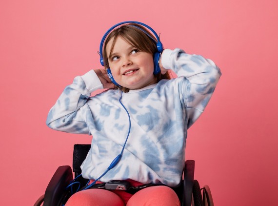 Child in wheelchair, wearing blue headphones