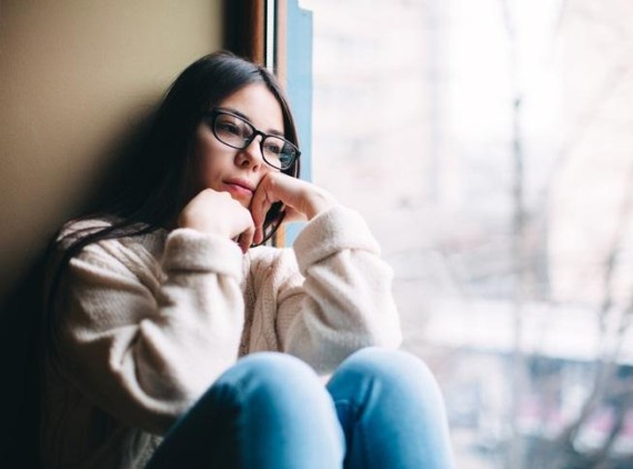 Pensive teen sitting next to window