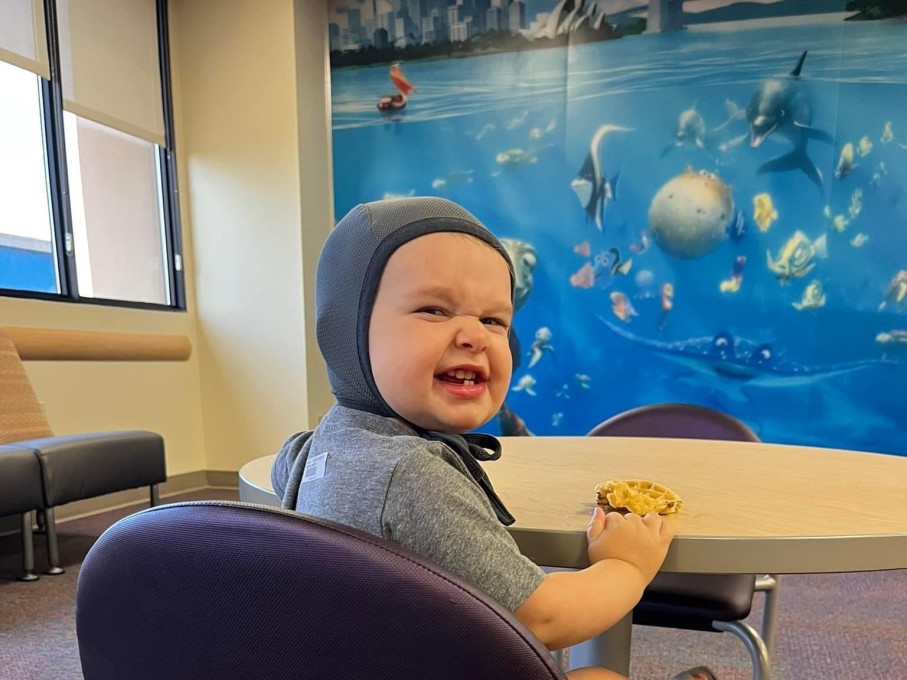 Smiling toddler sitting in chair, looking back