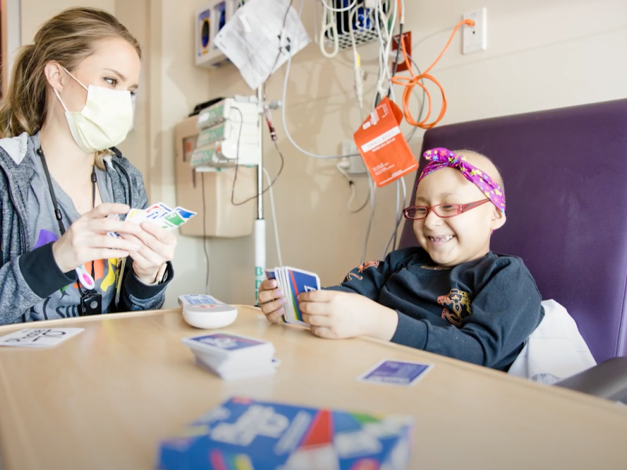 Provider and girl playing cards in hospital room